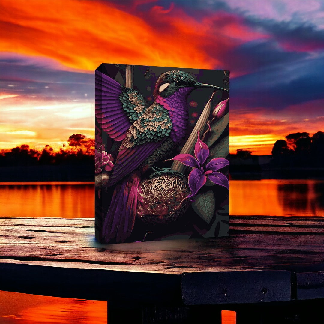 Peinture représentant un colibri aux plumes chatoyantes vertes, violettes et roses, entouré de fleurs exotiques, posée sur une table en bois. En arrière-plan, un ciel de coucher de soleil vibrant avec des nuances de rose, orange et bleu.
