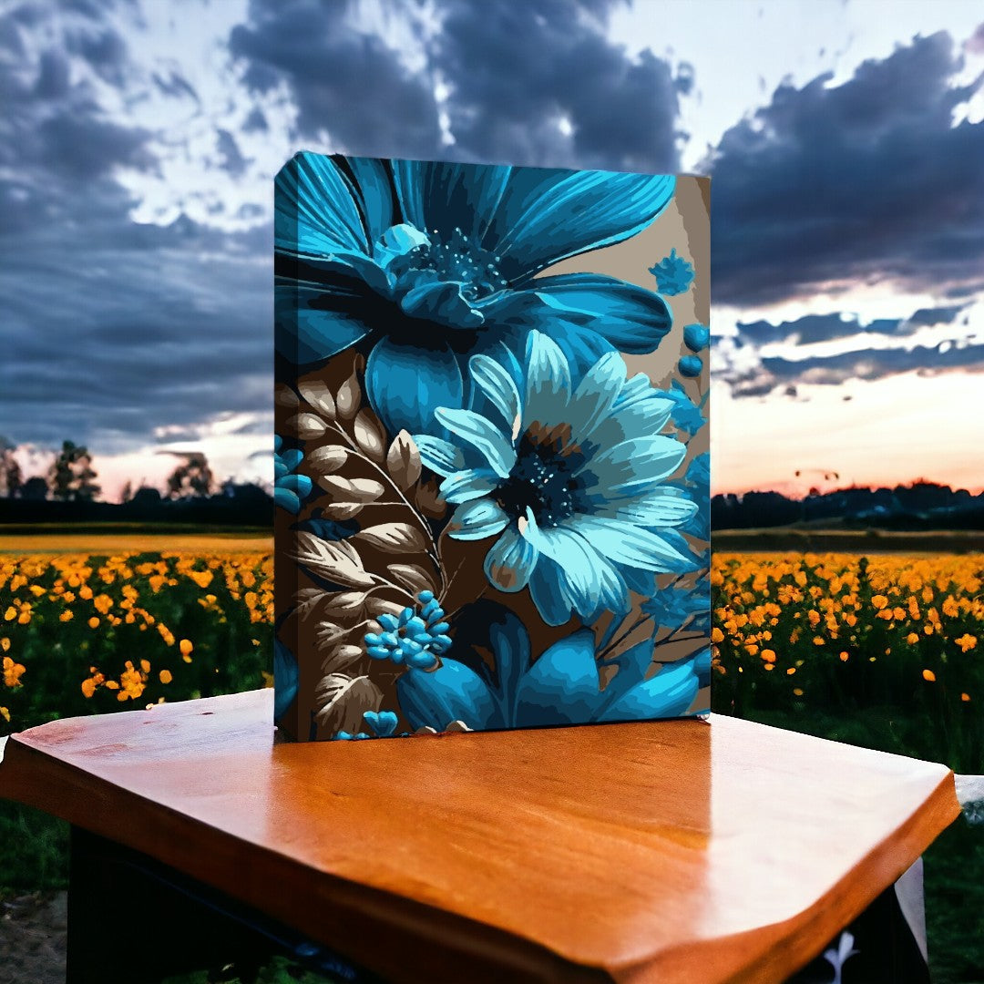Une peinture vibrante de fleurs bleues et de feuilles dorées est posée sur une table, avec un champ de fleurs jaunes et un ciel nuageux au coucher du soleil en arrière-plan.