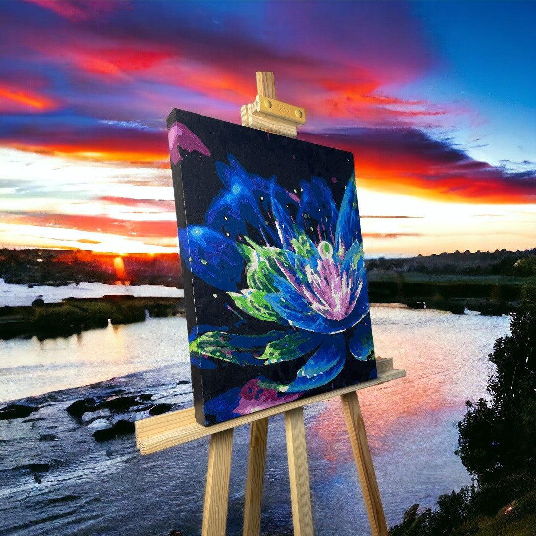 Une peinture colorée d’un lys sur un chevalet, avec un coucher de soleil vibrant et une rivière en arrière-plan